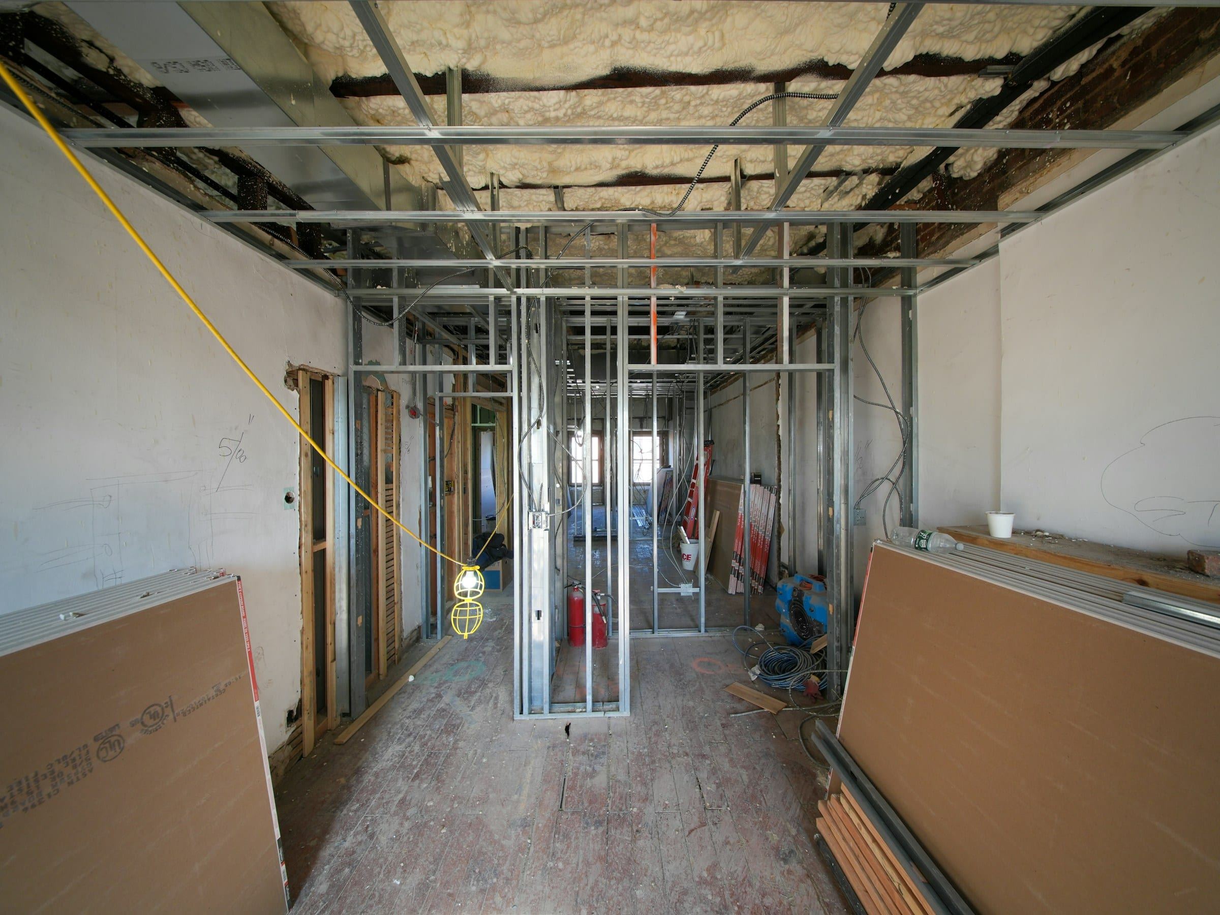 Interior renovation in progress with metal stud framing and drywall sheets