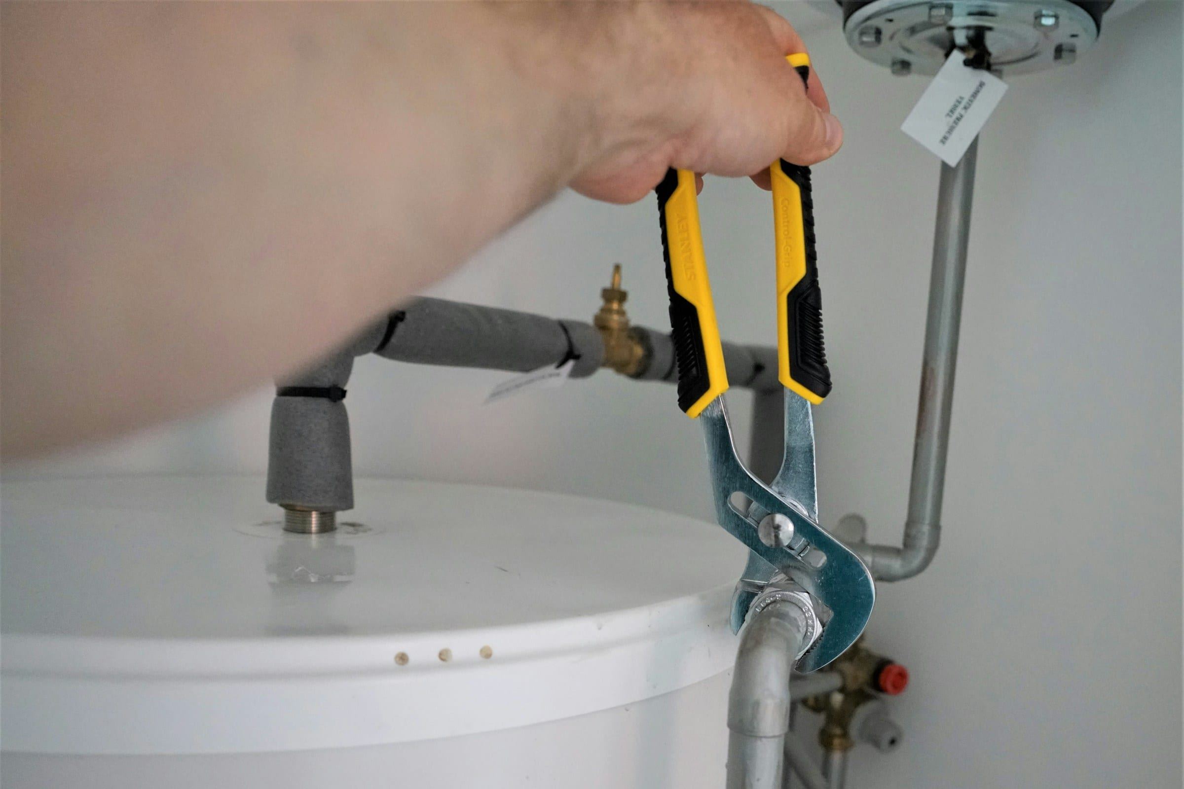 Hand tightening a water heater connection with pliers